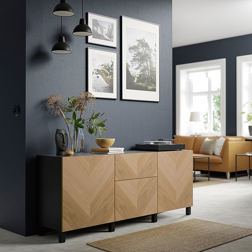 Habitación moderna con aparador de madera BESTÅ, colgantes negros, decoración elegante y asientos naranjas.