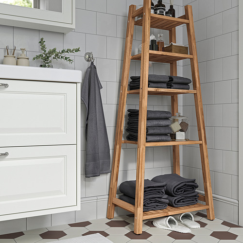 Estantería de madera de acacia en el baño con toallas y artículos de tocador.