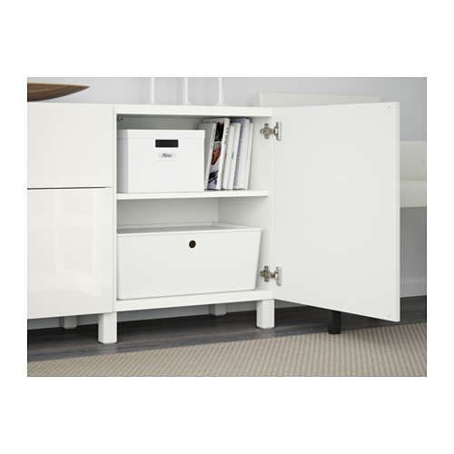Mueble de almacenamiento BESTÅ blanco con puerta abierta que revela cajas de almacenamiento y libros.