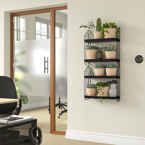 El estante de pared APOTEKARE sostiene plantas en macetas de color beige en estantes de metal negro cerca de una silla de oficina negra.