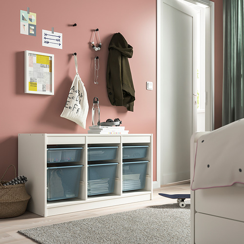 TROFAST: mueble de almacenaje blanco con cajas de malla azul. Ganchos montados en la pared, alfombra y monopatín.