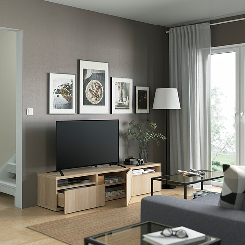 Sala de estar moderna con televisor en una elegante consola multimedia contra una pared oscura, rodeada de arte enmarcado.