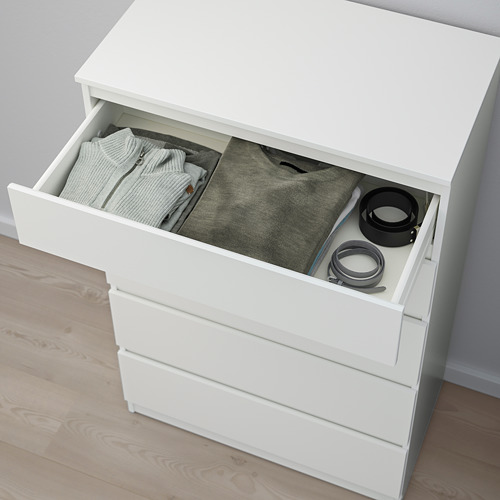 Cómoda blanca con un cajón abierto que deja ver la ropa doblada y los objetos pequeños. Incluye un kit de anclaje para mayor seguridad.