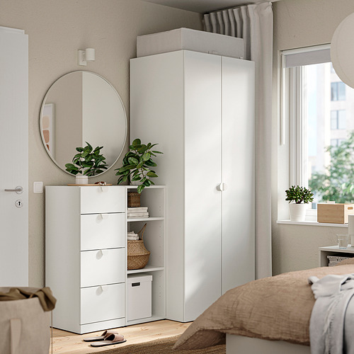 Cómoda blanca moderna en una habitación acogedora, con espejo, plantas y cajas de almacenamiento.