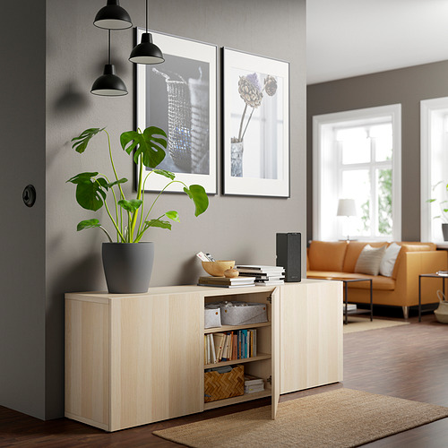 Salón moderno con aparador BESTÅ, estantes ajustables, libros, decoración, plantas y apliques.