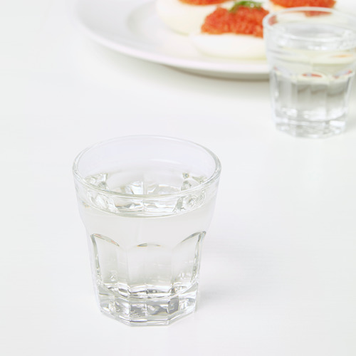 Dos vasos con hielo descansan sobre una mesa blanca, junto a un plato con comida.