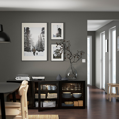Comedor moderno con almacenaje BESTÅ. Armario oscuro, arte, jarrón de cristal y lámpara colgante contra paredes de color gris oscuro.