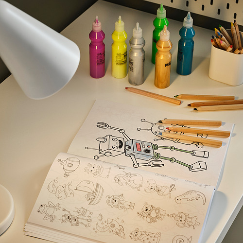 Escritorio colorido con materiales de arte y lámpara que ilumina un libro para colorear de robots.