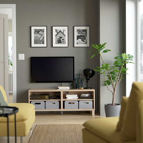 Gray living room with BESTÅ tv bench, flat screen, yellow chairs, green plant, black lamp, and photos above tv.