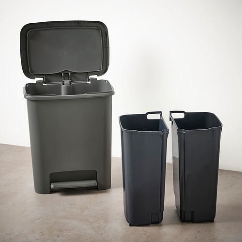Dos cubos de basura de plástico gris con la tapa abierta a la izquierda, dos cubos sin tirador a la derecha, todos ellos sobre un suelo beige contra una pared blanca.