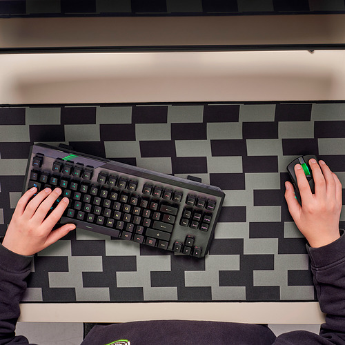 Persona escribiendo y usando el mouse en el panel de juego a cuadros.