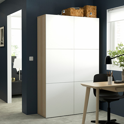 Mueble blanco BESTÅ con múltiples estantes, más alto que una silla/lámpara, diseño minimalista.