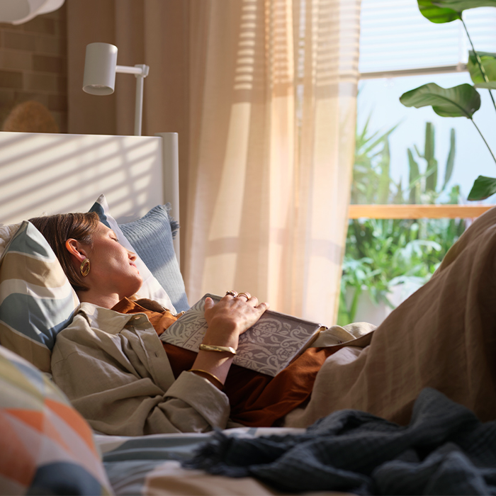 Mujer durmiendo plácidamente en la cama sosteniendo un libro sobre el pecho.