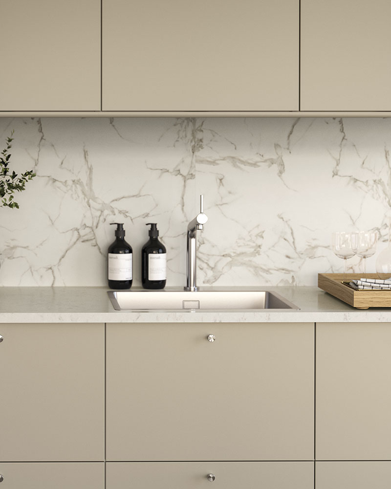 A light, modern kitchen has sleek, beige HAVSTORP doors and fronts with stainless steel knobs and a stainless steel sink.