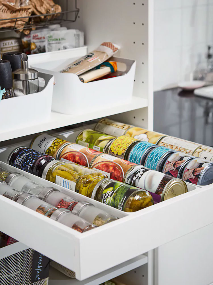 White kitchen shelf with a tray-style drawer full of spice jars and condiments, neatly organized in a clean