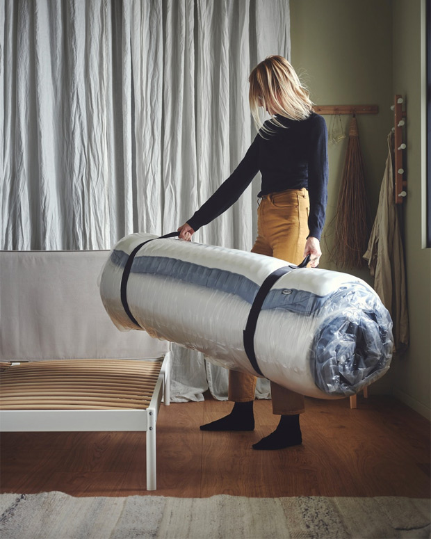Woman holding a bundle of a rolled up mattress ready to place on the bed