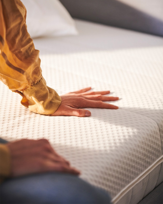 One-handed shot measuring the thickness and softness of a mattress