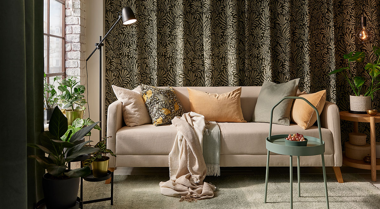 A living room with a LINANÄS 3-seat sofa in the center, with two HOLMVI throws on top and a BURVIK side table.