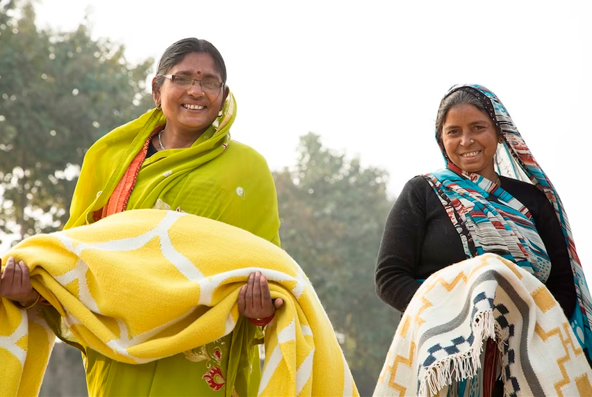 Two Indian women holding colorful textiles
