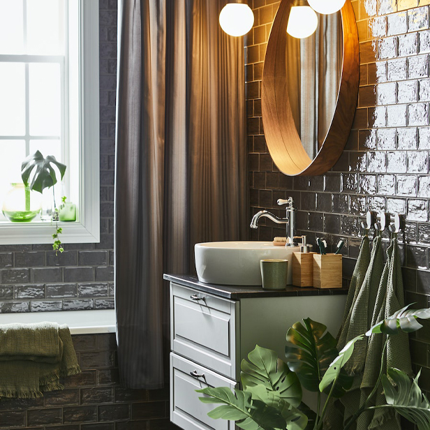 A corner of a bathroom with green tones featuring a TÄNNFORSEN/TÖRNVIKEN bathroom cabinet with sink and drawers, along with a DRAGAN toothbrush kit and soap dispenser.