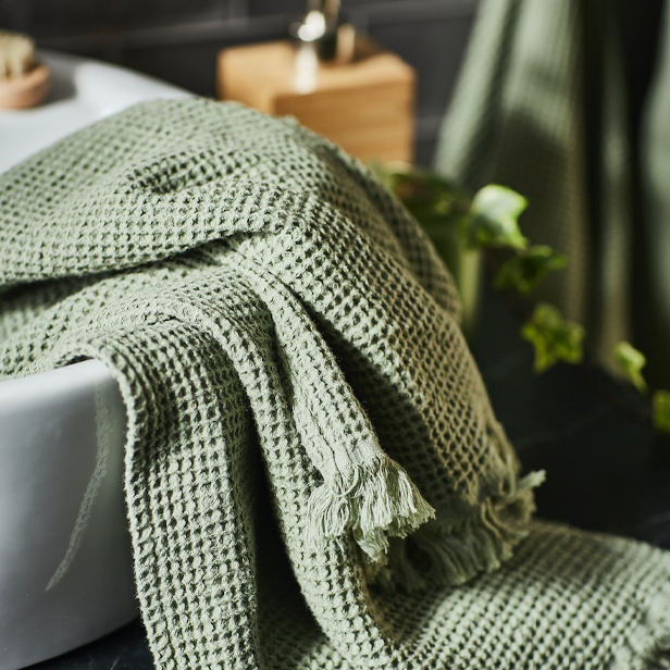 A TÖRNVIKEN washbasin with a green VALLASÅN bath towel.