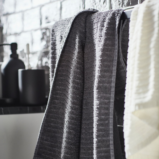 A VÅGSJÖN bath towel with a GANSJÖN bathroom set in the background.