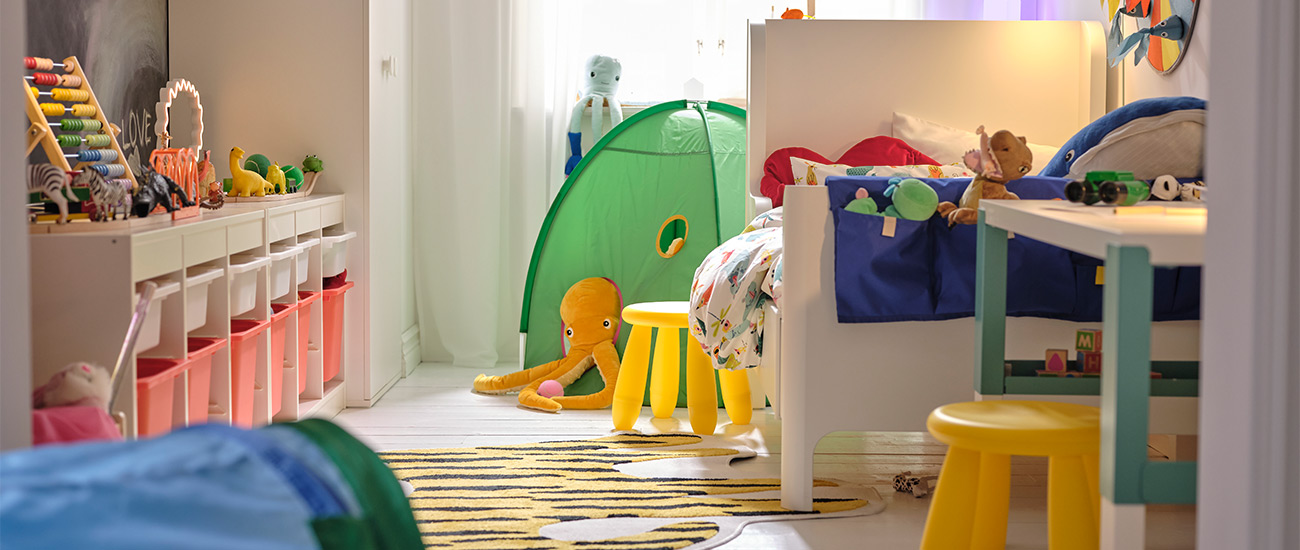 Colorful kids' room with toys, bed, table, and children's tent.