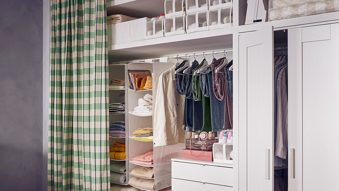 Open wardrobe with curtain, neatly arranged shelves, hanging space, and textile storage.