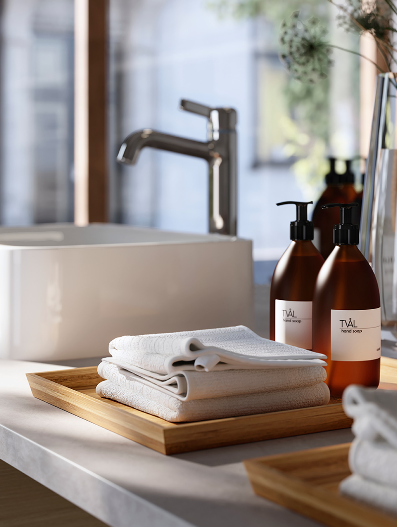a towel on a wooden tray, there are bottles of toiletries, there is a bathroom sink with modern faucet