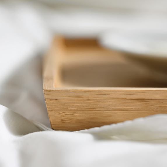 Macro detail of a wooden tray on a white blanket