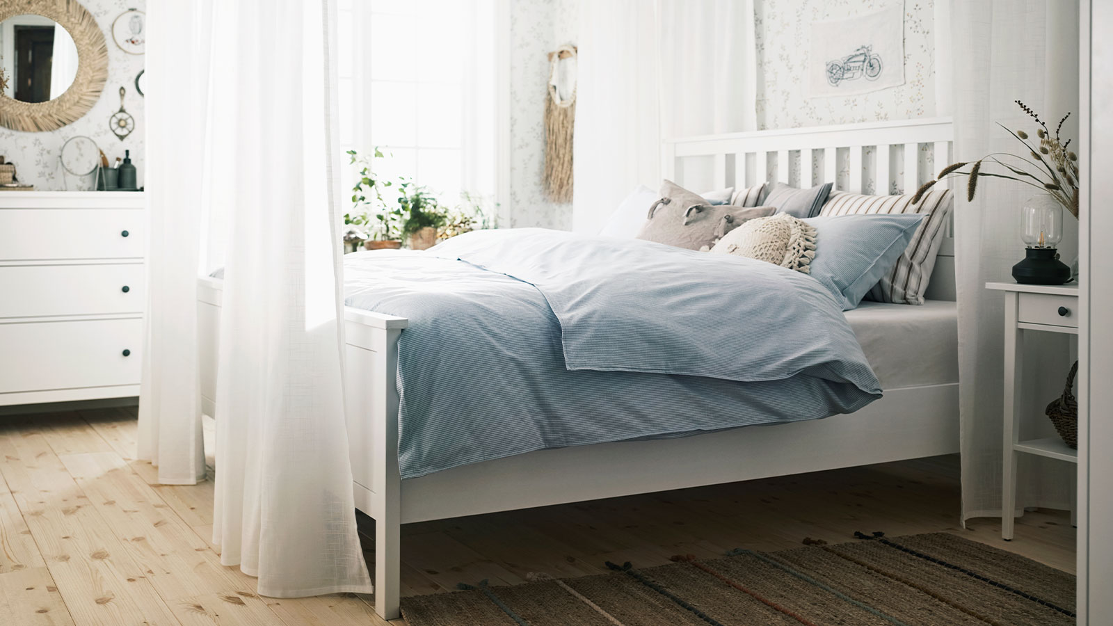 A large, traditional style bed surrounded by ethereal sheer white curtains in the middle of the room 