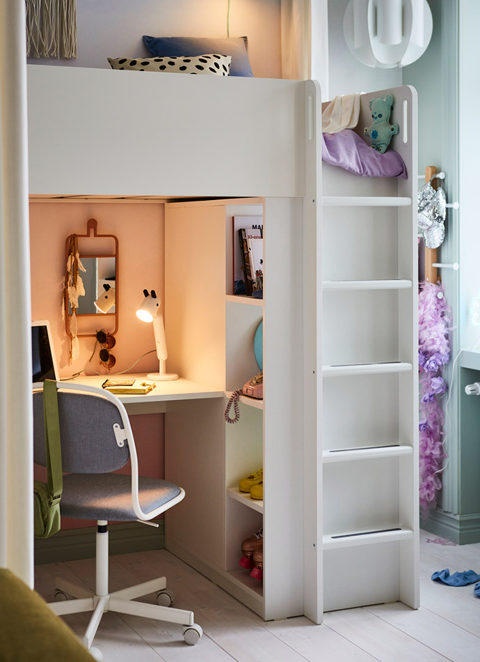 The image shows a white loft bed with a desk underneath, a gray chair, and shelves. The atmosphere is youthful and organized.