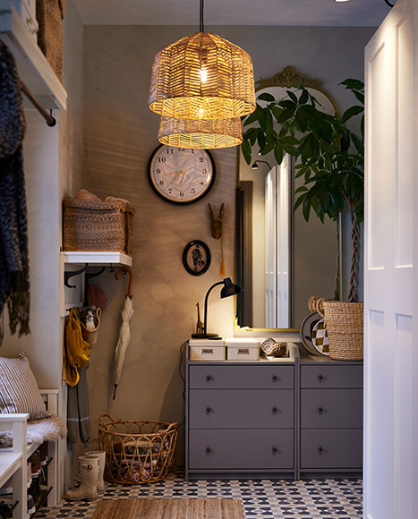Hallway featuring a wicker pendant lamp, grey dresser, mirror, and wall clock.