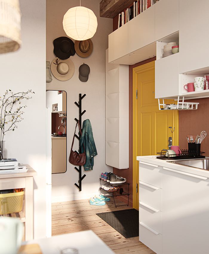 Hallway with a wall-mounted coat rack, hats, and shoes, next to the entrance of a modern kitchen.
