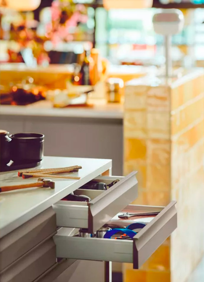 Open kitchen drawers reveal organized utensils. Functional, bright ambiance with beige and gray tones.