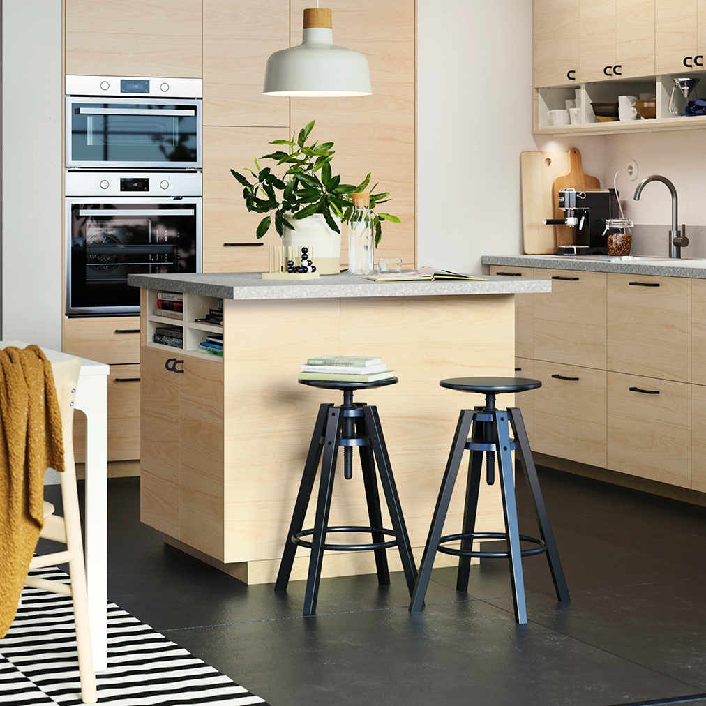 Spacious modern kitchen with wood veneers, there is a kitchen island with high stools.