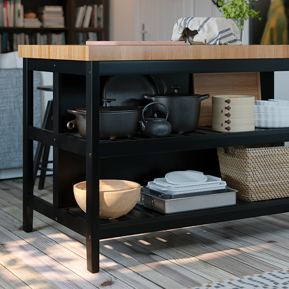 Detail of the lower part of a kitchen island with black base, oak countertop, wooden pans and bowls
