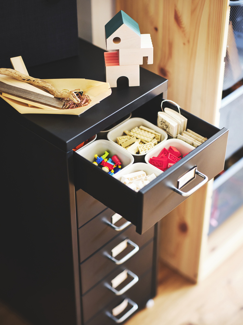 Black drawer unit with an open drawer revealing organizers filled with toy blocks. A tidy and functional ambiance for children's play.