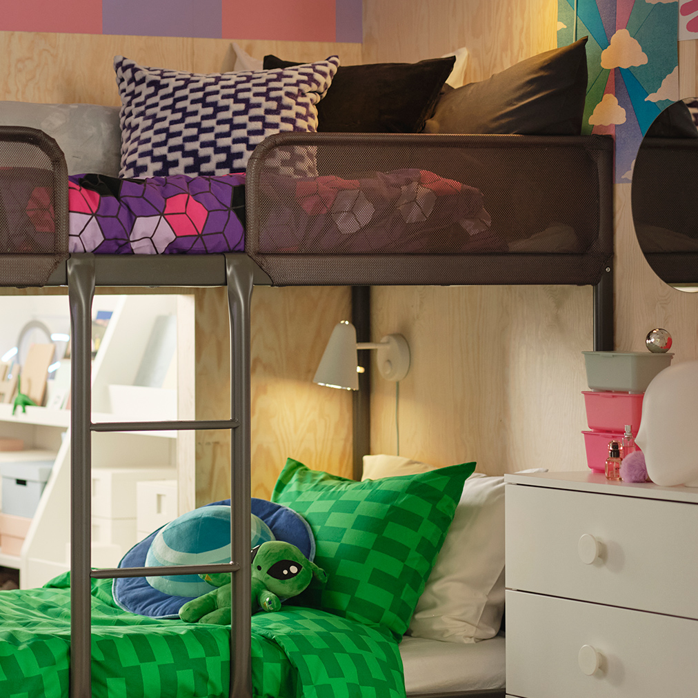 Modern bunk beds with green and purple bedding, and a light wood wall. A fun and youthful ambiance in a shared bedroom.