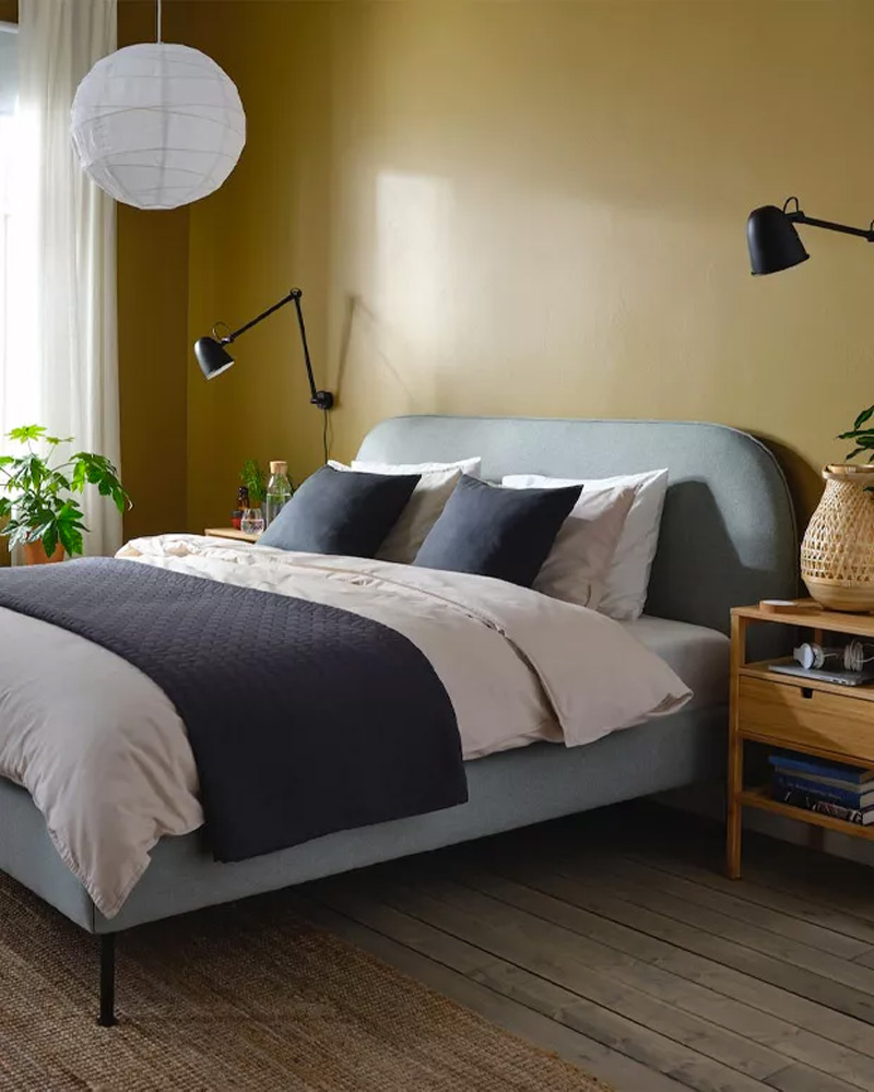 A bed covered with ULLVIDE sheet and pillow set next to a NORDKISA nightstand.