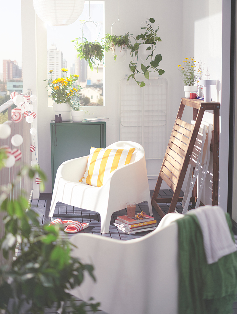 Outdoor environment on a balcony with two plastic outdoor armchairs, there is a folding table leaning against the wall.