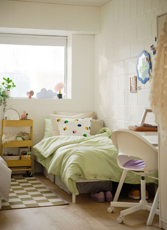 student room, with a bed that has a light green duvet, a modern and creative chair and desk