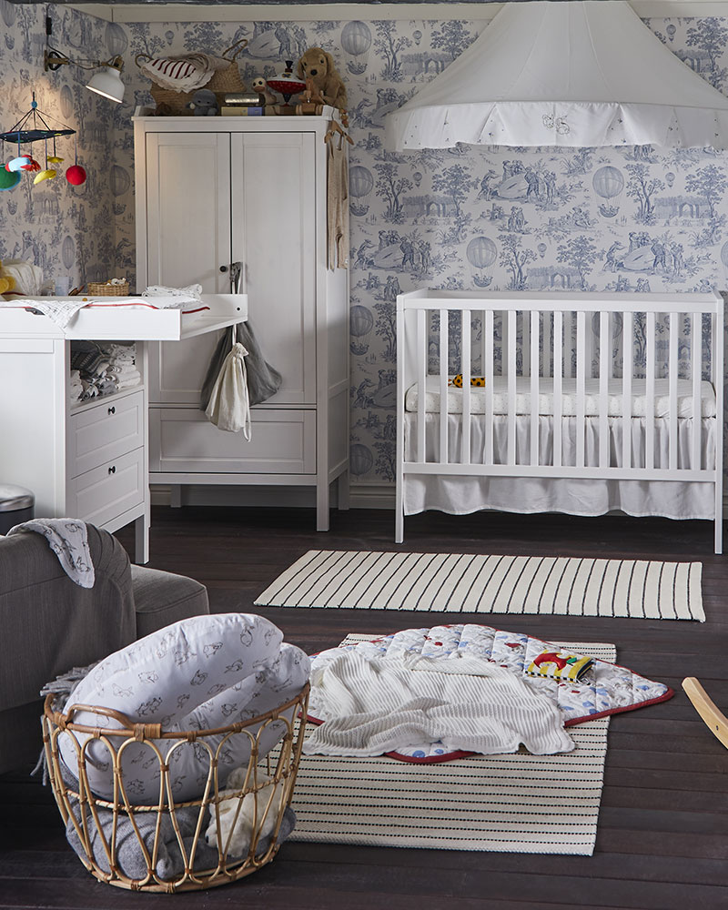 A baby room with a SUNDVIK crib in the back, a SUNDVIK wardrobe to its left, a SUNDVIK changing table, and a SNIDAD basket in the front.