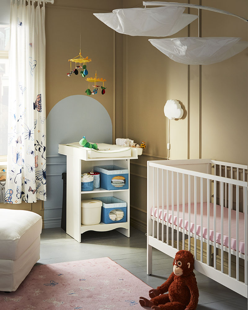 A baby room with a SMÅGÖRA crib, a SMÅGÖRA changing table, and a DJUNGELSKOG stuffed animal on the floor.