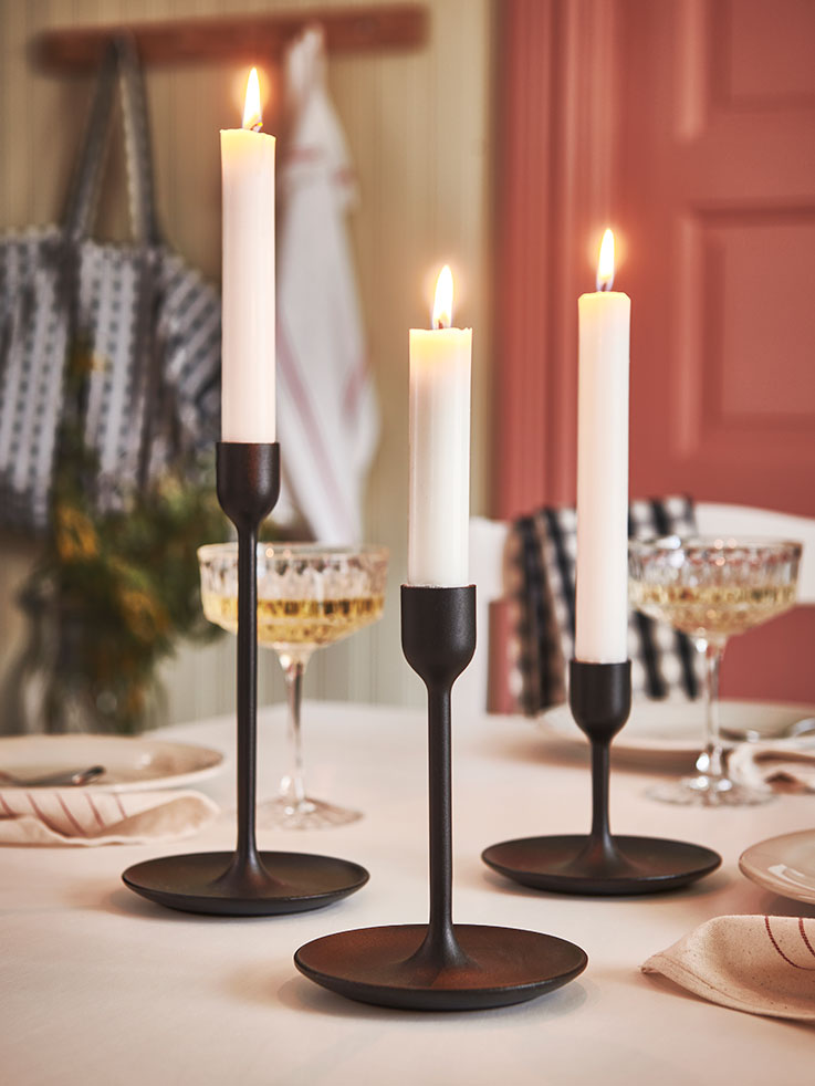 Modern vintage style black candlesticks, with candles on a table