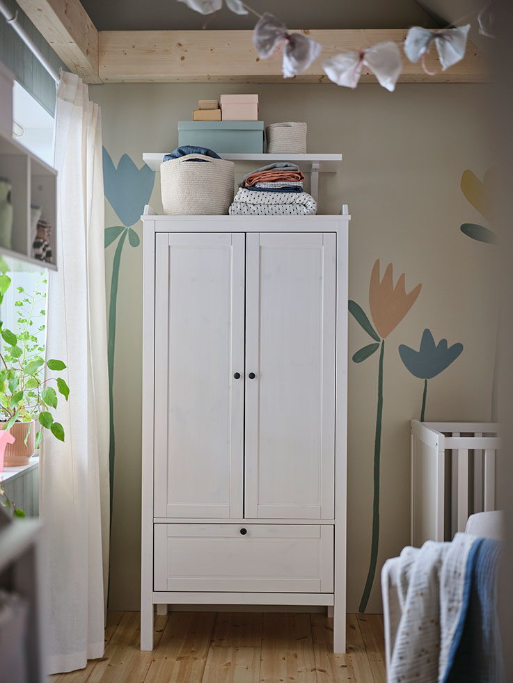 White baby closet next to a window and on the other side you can see part of a crib.