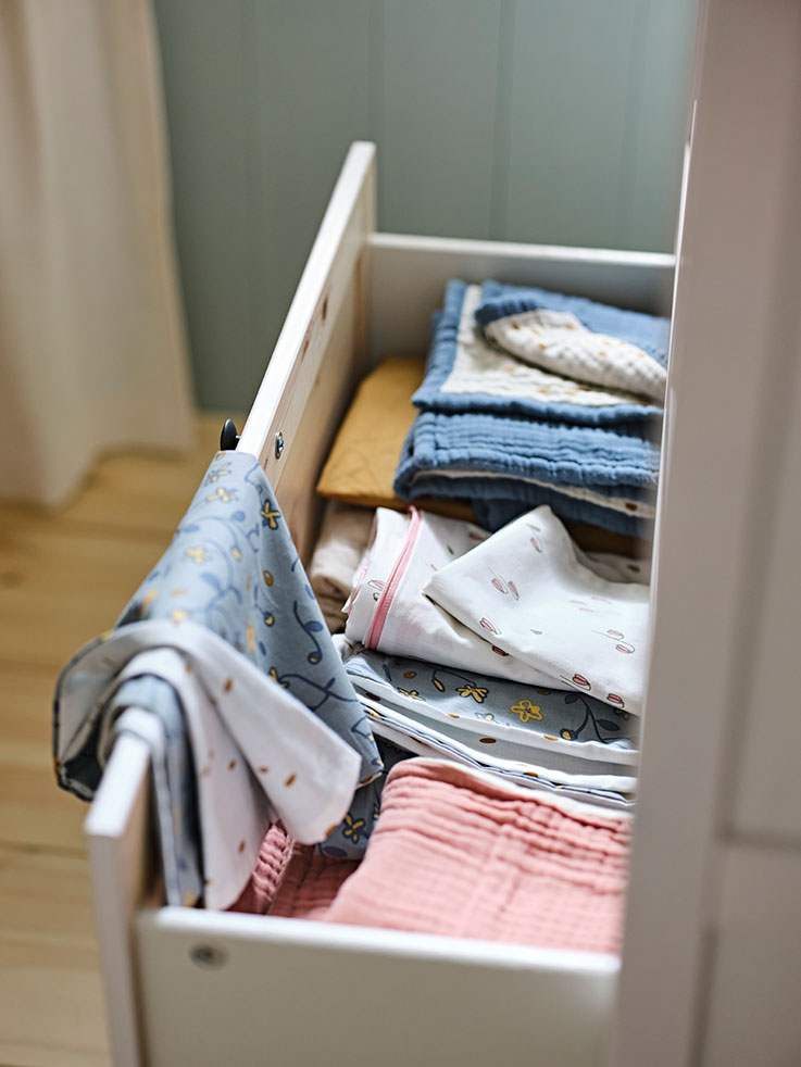 An open drawer is seen, children's clothes inside.