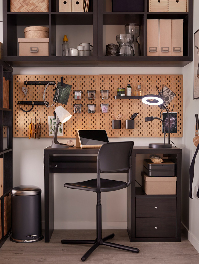  Dark office desk with computer, lamps, and organized shelves. Workspace atmosphere.