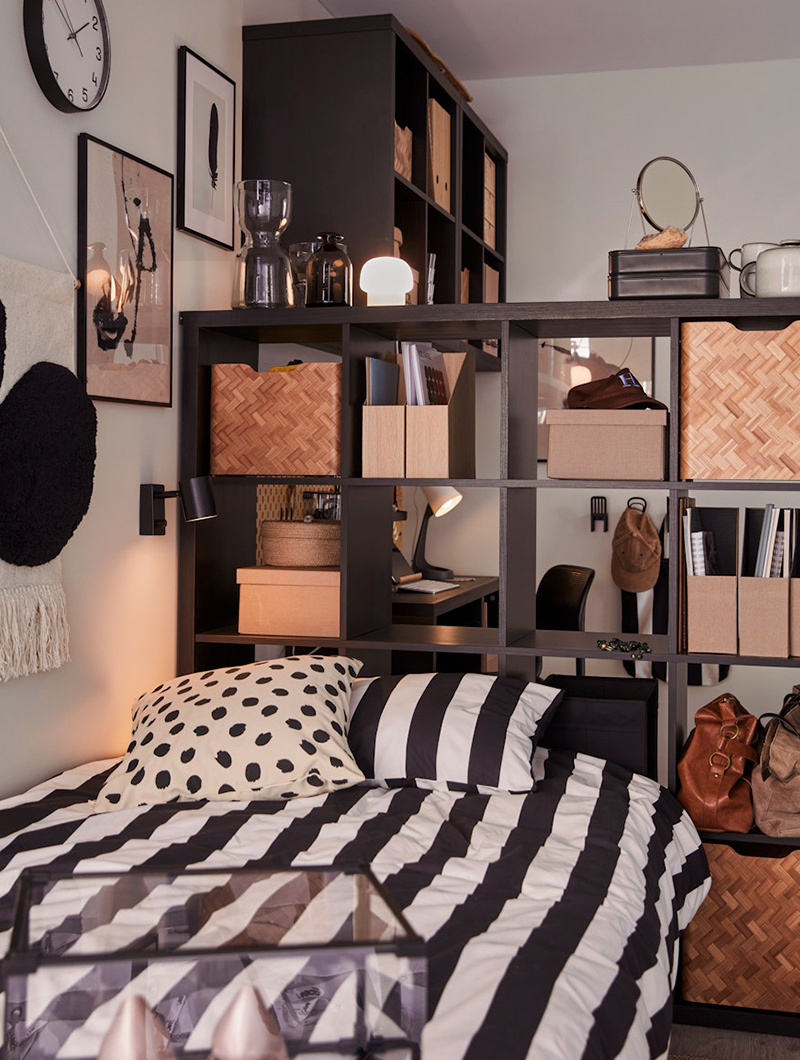  Bedroom with black and white striped bed, dark shelving unit with decor, and desk.