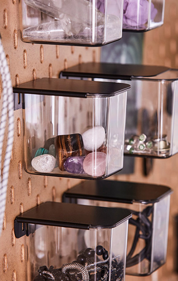  Clear organizing baskets on a pegboard, with crystals and jewelry. Tidy ambiance.
